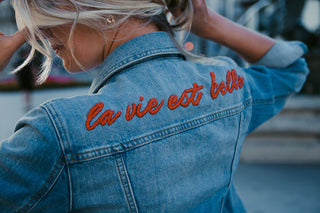 Jeansjacke mit gesticktem Schriftzug „la vie est belle“ in Orangerot auf dem Rücken